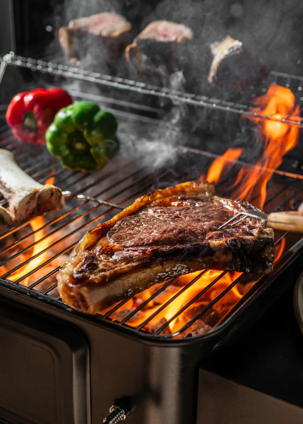 Barbacoa de carbón Create Smokey Pro con regulador de brasas y mesa plegable: la rejilla superior en uso a la vez que la parrilla principal