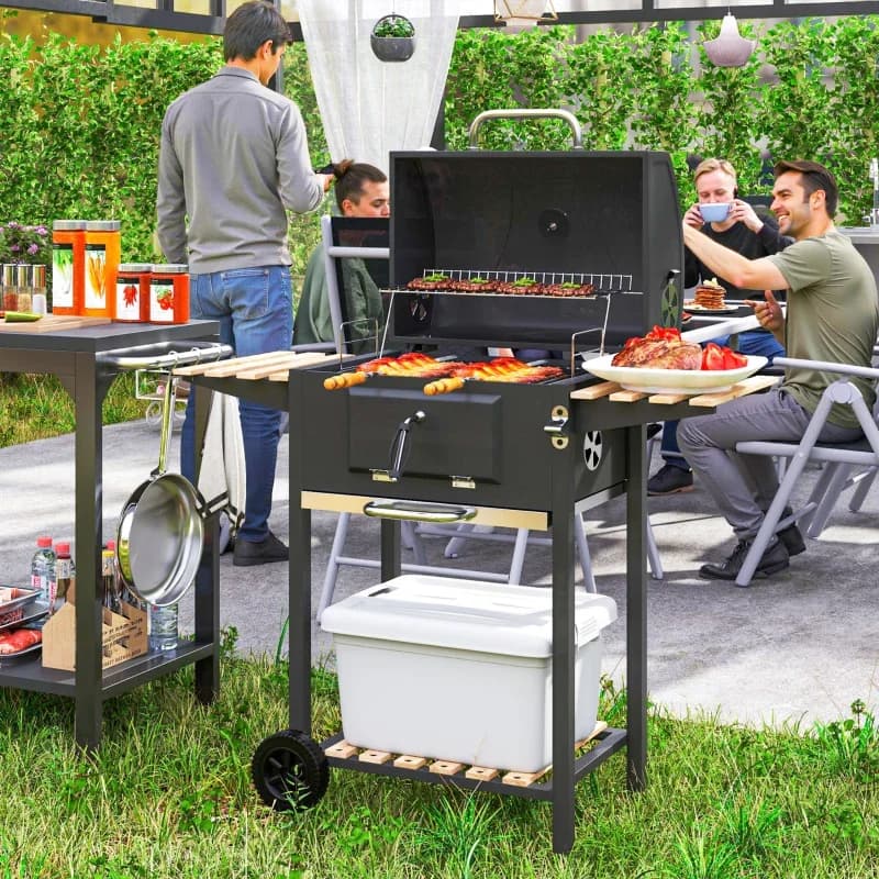 Barbacoa de carbón Outsunny 112 cm con brasa regulable y tapa: en uso durante una barbacoa