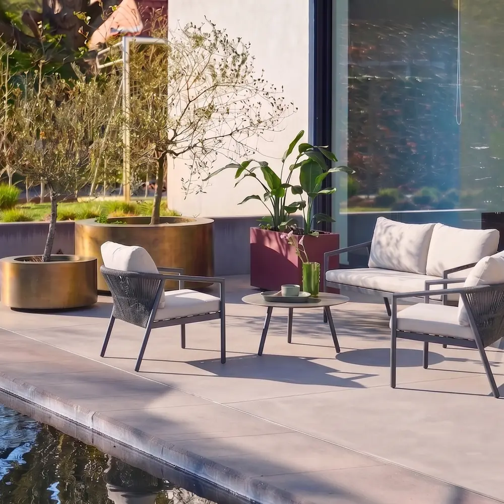 Conjunto de jardín de aluminio y cuerdas gris para 4 personas con mesa redonda: el conjunto en un rincón del jardín, con los cojines puestos y la mesa baja