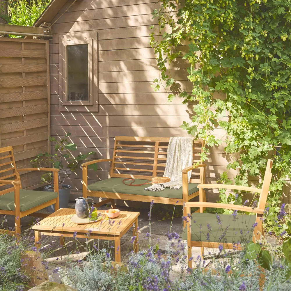 Conjunto de jardín de madera de acacia para 4 personas, en verde kaki, verde grisáceo o beige: el conjunto en un rincón del jardín, con los cojines puestos y la mesa baja