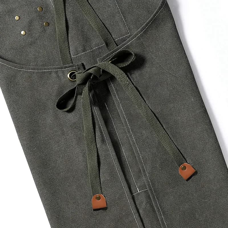 Delantal de lona de algodón negro con bolsillos y tirantes cruzados: el cordón elástico de ajuste en el bajo