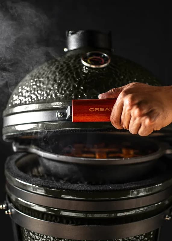 Barbacoa kamado Create de cerámica 16" negra: cerrando la tapa por la manija de bambú, con el carbón encendido dentro