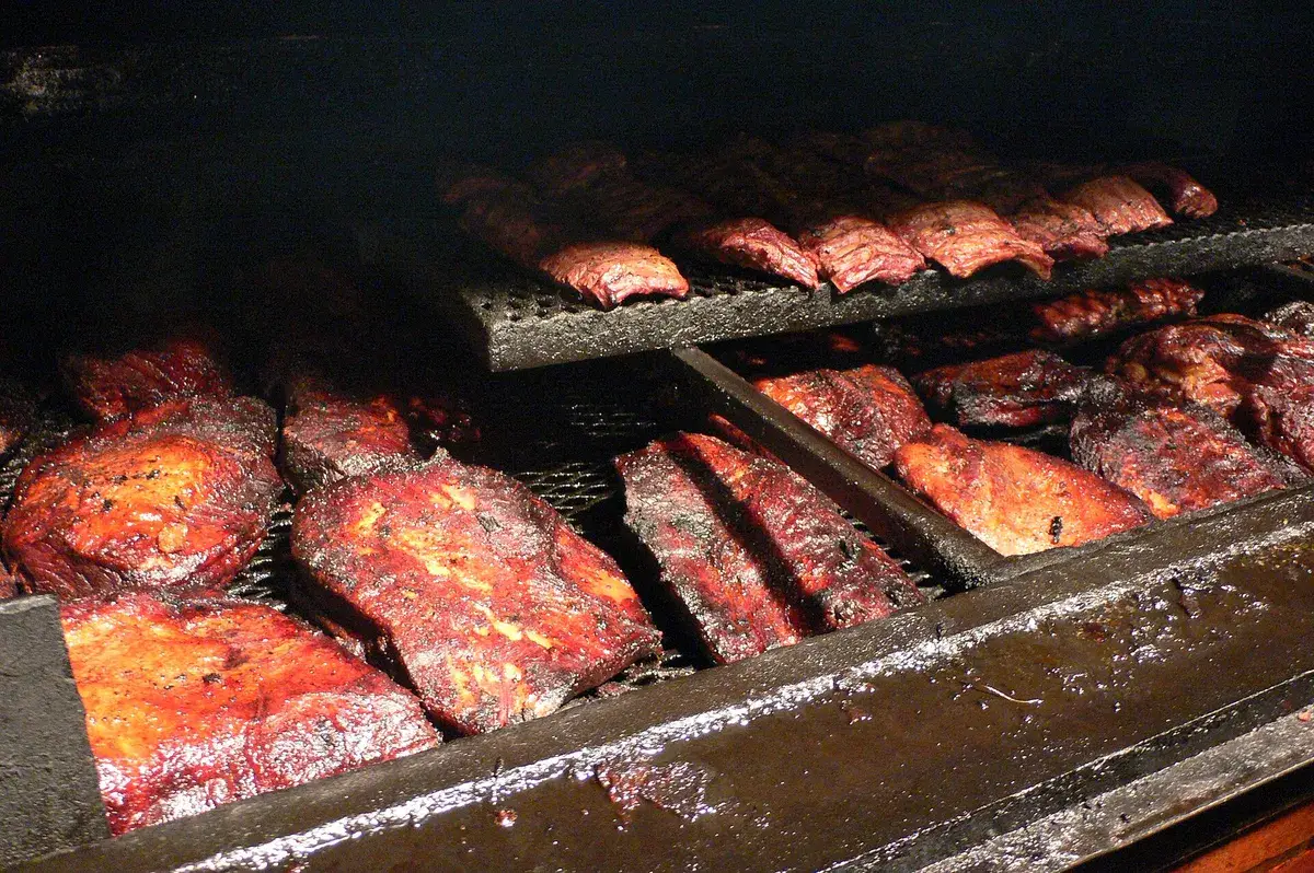 Briskets enteros y costillares ahumándose en la parrilla de un ahumadero de Texas