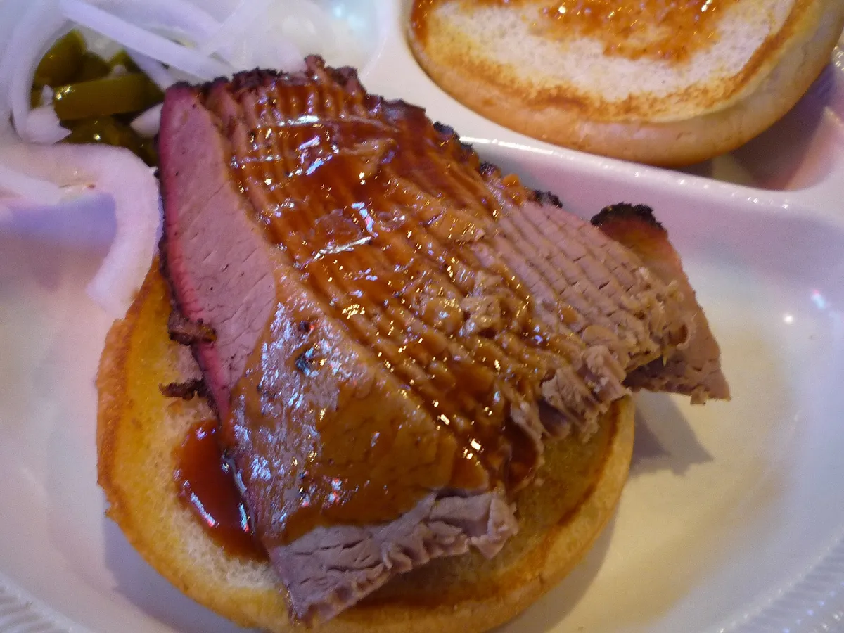 Bocadillo de brisket ahumado en lonchas con salsa barbacoa, cebolla y jalapeños