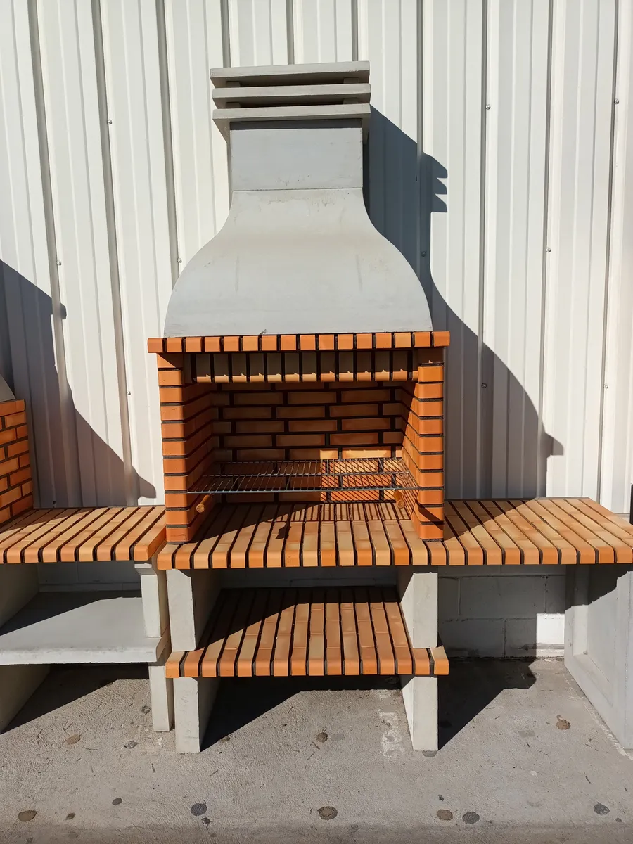 Barbacoa de obra modular de ladrillo con campana, chimenea, parrilla y repisas laterales a ambos lados