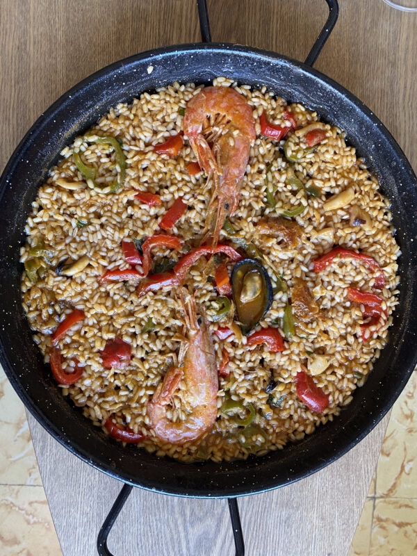 Detalle de paella recién hecha con gambas, mejillón y pimientos en una sartén de barbacoa