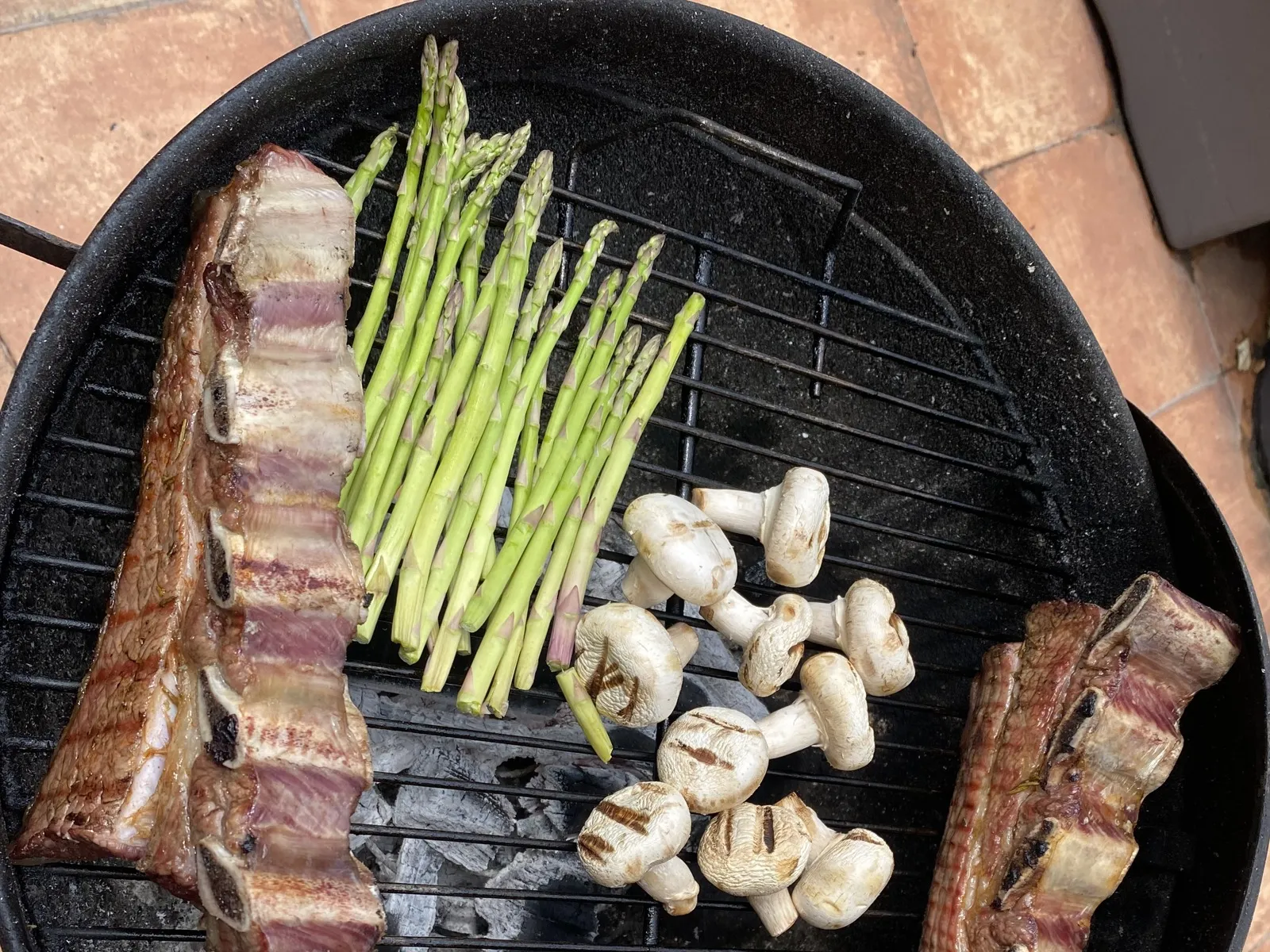 Espárragos verdes y champiñones sobre la parrilla de una barbacoa de carbón