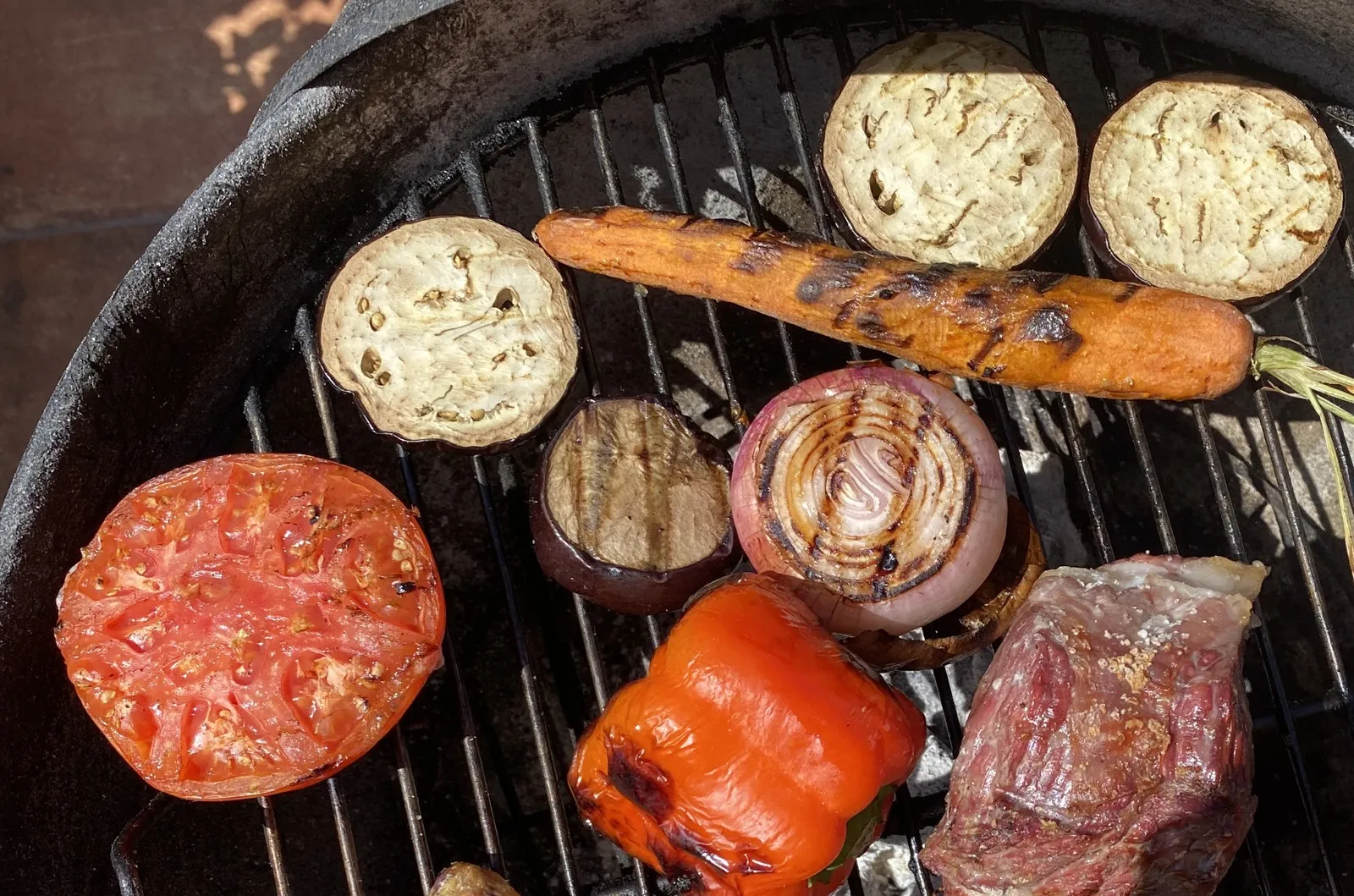 Verduras a la brasa en una barbacoa de carbón: tomates partidos, pimiento rojo, berenjena, cebolla y zanahoria