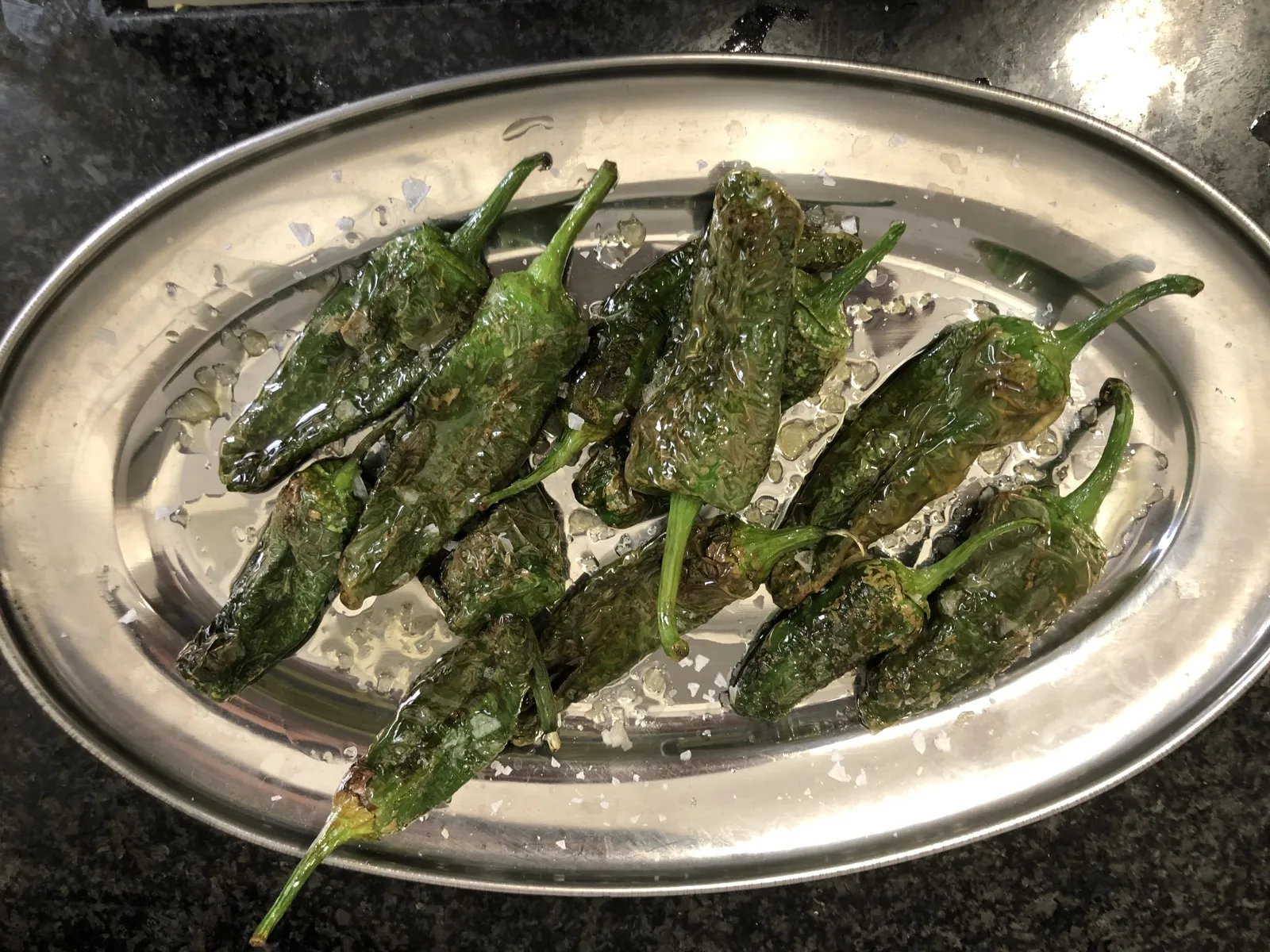 Pimientos de Padrón hechos a la brasa servidos en una fuente de acero