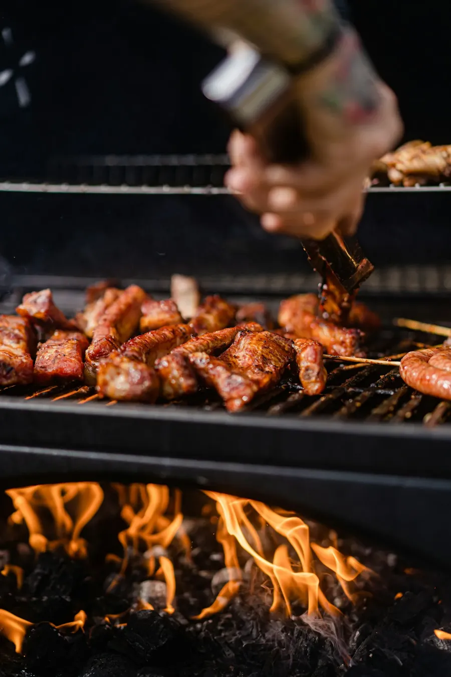 Brasas de carbón encendidas y llamas vivas bajo la parrilla de una barbacoa