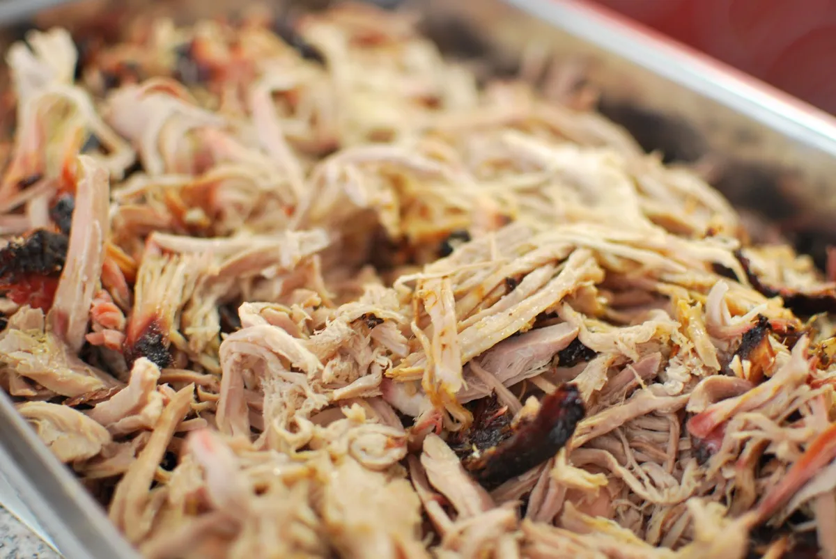 Pulled pork recién desmechado en una bandeja, con las hebras de cerdo y los trozos de corteza ahumada