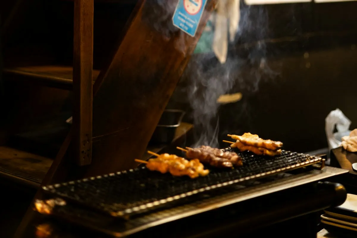 Brochetas de yakitori asándose sobre la brasa en un puesto japonés
